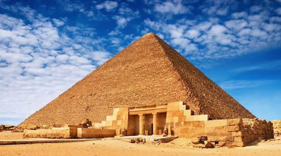 View of the Pyramids of Giza with the sun setting behind them in Egypt